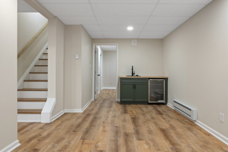 completed basement remodel showing stairs and bar sink with fridge