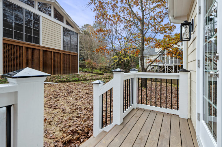 The porch of a detached building that is used as an office with the primary house in the background