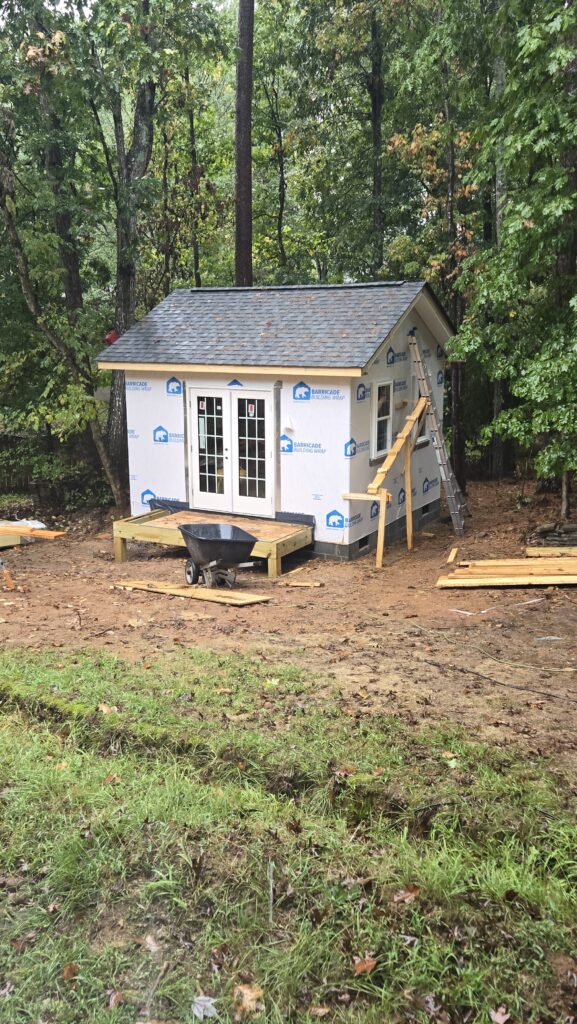 Exterior detached structure halfway though the build process with framing, roof, windows and doors in place. 