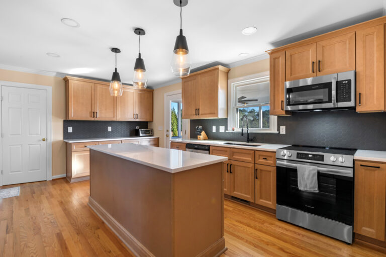 a remodeled kitchen showing cabinets, island, new lighting