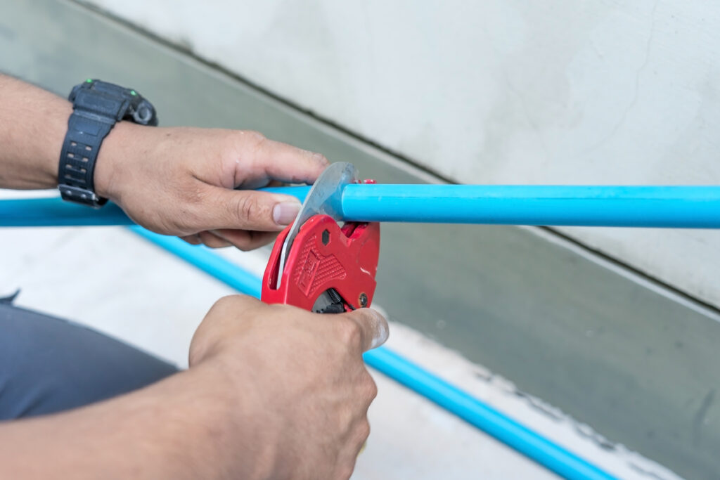 What Every Homeowner Needs to Know About Polybutylene Piping. shows a pipe being cut by a plumber.