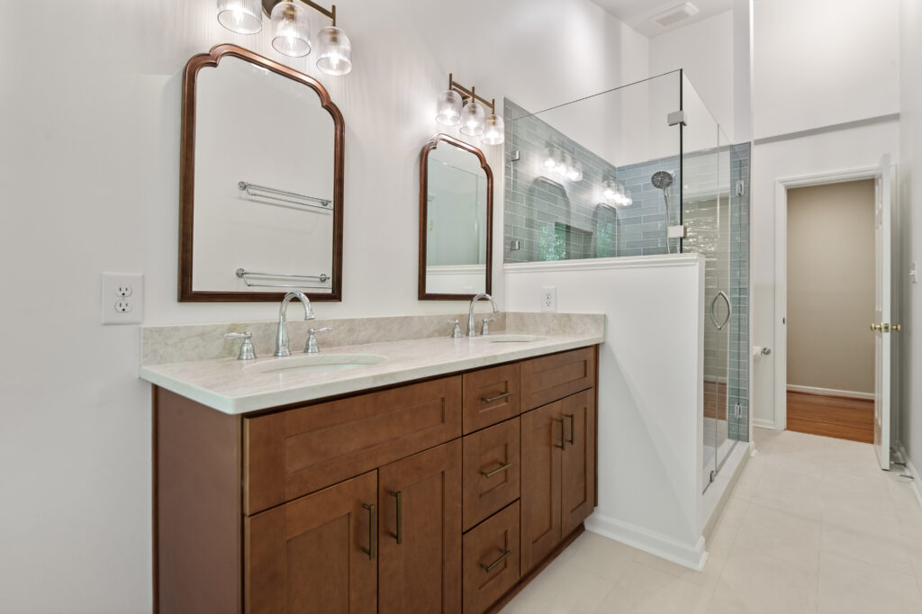 Renovated bathroom with wood vanity and blue tile in shower
