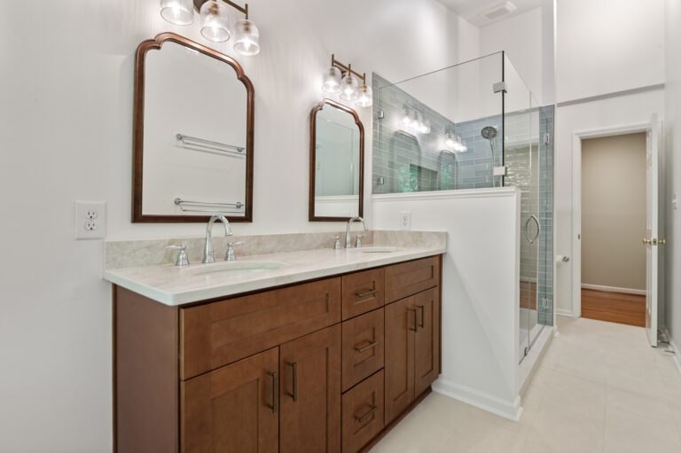 Renovated bathroom with wood vanity and blue tile in shower