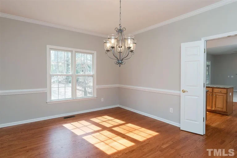 Realtors listing image of a dining room with wood floors, chair rail, and light fixture.